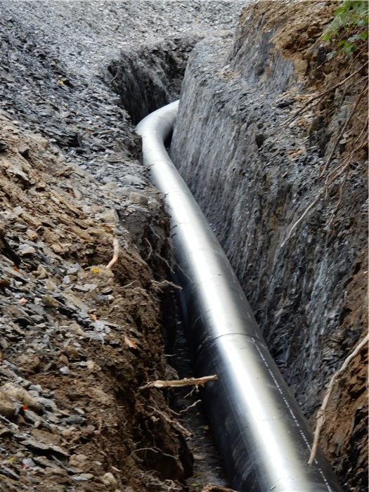 The lowest string of polyethylene pipe in its trench through rock 8 Sept 2015